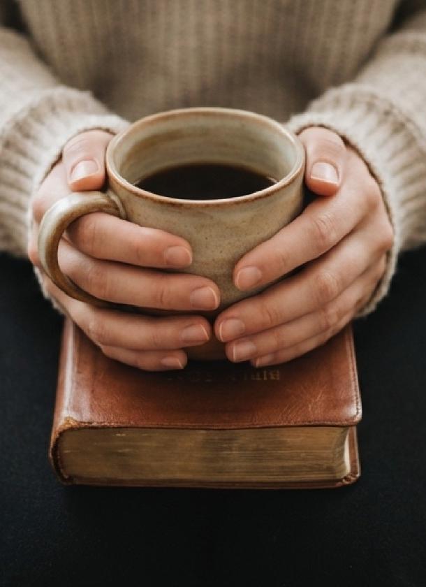 Теплий напій у руках над книгою